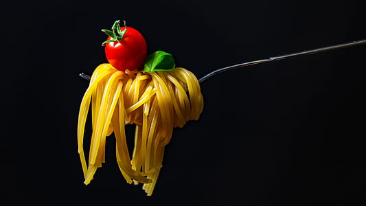 rolled pasta in gray metal fork with red cherry tomato thumbnail