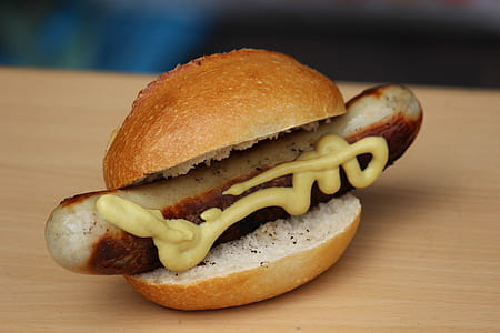 sausage burger with mustard on wooden surface thumbnail