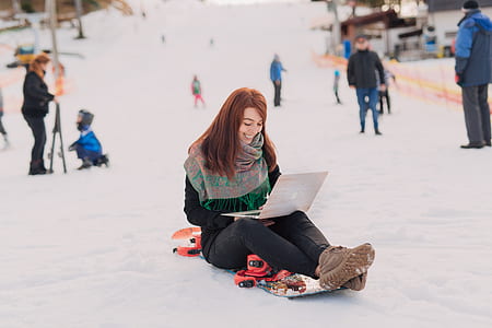 woman sitting in snowfield while using laptop thumbnail