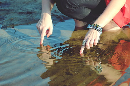 person's finger tips on body of water thumbnail