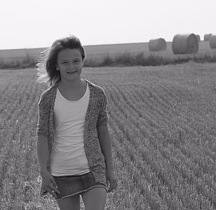 grayscale photo of girl standing on grass field thumbnail
