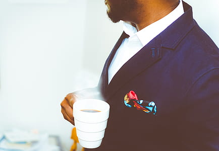 man wearing black suit holding white mug with coffee thumbnail