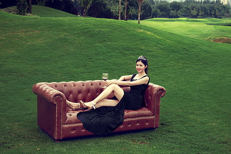 woman wearing black split dress lying on brown Chesterfield sofa thumbnail