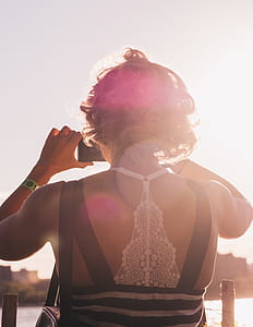 woman in black sleeveless dress holding black smartphone taking photo thumbnail