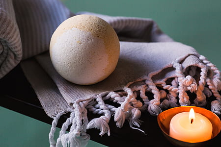bathbomb on top of purple textile near the candle thumbnail