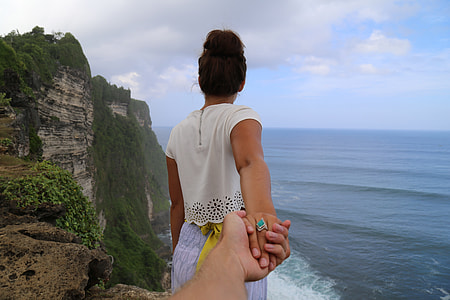 person holding woman on mountain cliff thumbnail