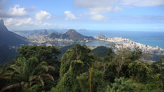 aerial view of coastal area with buildings surrounded by mountains during daytime thumbnail