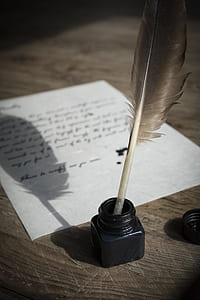 black quil pen on ink case beside paper thumbnail
