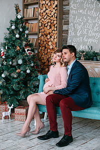 man hugging woman while seating on teal couch thumbnail