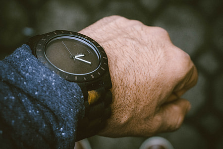 person wearing round black analog watch at 12:05 thumbnail