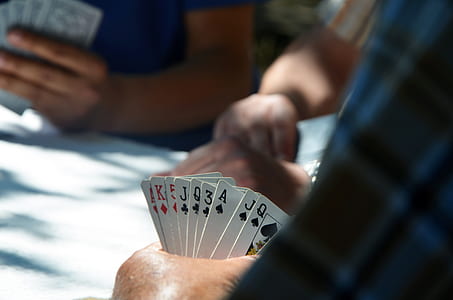left person hand holding pile of playing cards thumbnail