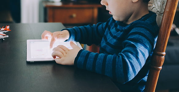 boy sitting on chair using tablet computer thumbnail