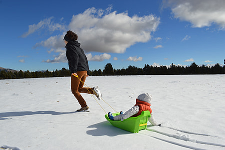 toddler riding on green plastic sled thumbnail