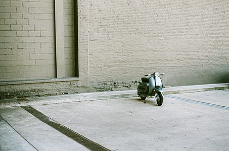 blue motor scooter parked beside building thumbnail