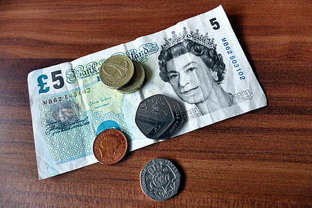 5 banknote and coins on brown wooden board thumbnail