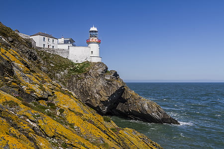 white lighthouse facing ocean under blue sky thumbnail