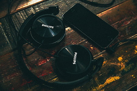 black Philips headphones and smartphone won wooden surface thumbnail