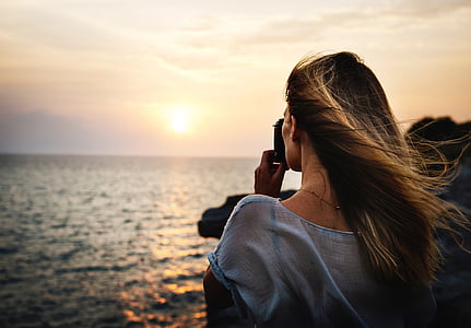 woman taking picture of body of water thumbnail