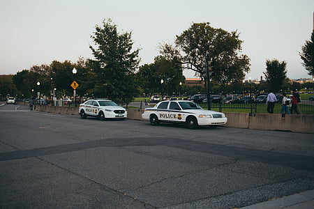 two white police cars parked beside road during daytime thumbnail