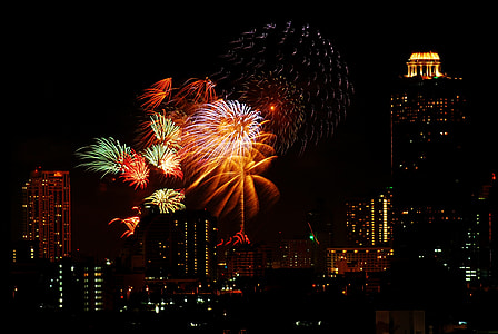 lighted fireworks surrounded by buildings thumbnail