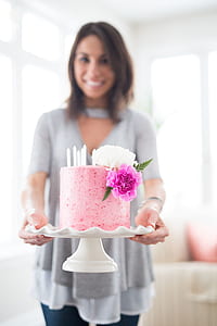 woman showing pink cake on white cake tray indoor thumbnail