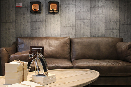 bundle of books on oval brown wooden coffee table in front of brown leather couch thumbnail