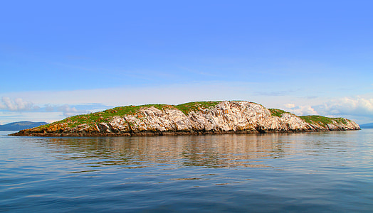 green grass covered island with calm water thumbnail