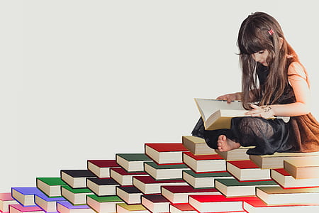 girl reading book on assorted-color book lot thumbnail