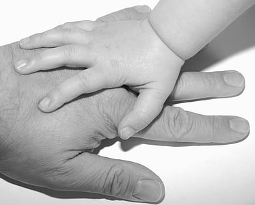 close up photograph of grayscale person left hand under baby hand thumbnail