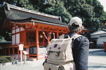 man carrying bucket backpack looking at pagoda house thumbnail