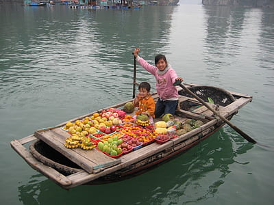 girl and boy riding on boat with bunch of fruits thumbnail