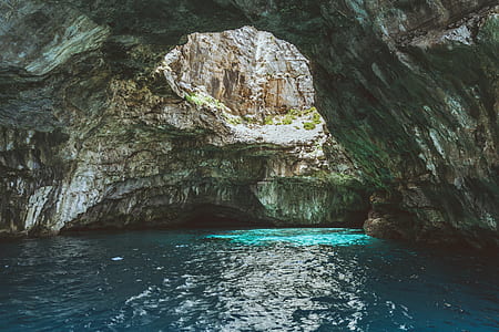 blue body of water under rocky cave thumbnail