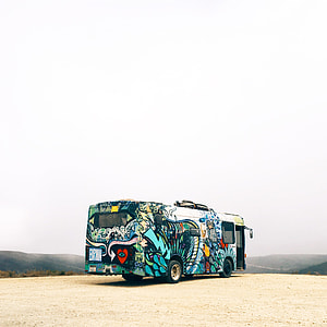 blue and multicolored bus on gray sand facing the mountain range thumbnail