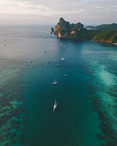 aerial photograph of boats on body of water near island thumbnail