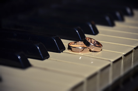 two pink gold-colored rings placed on piano keys thumbnail