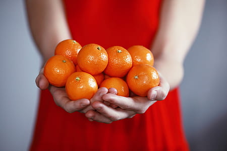 person holding tangerine fruits thumbnail