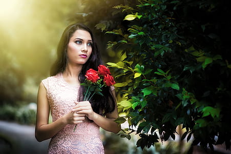 woman in pink dress holding red roses thumbnail