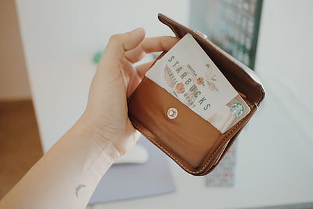person holding brown StarBucks leather coin purse thumbnail
