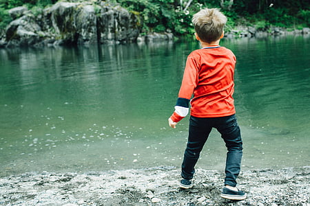 boy wearing orange long-sleeved shirt across body of water thumbnail