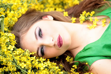 woman in green shirt lying on yellow flower field thumbnail