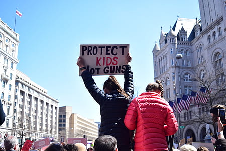woman holding signage with protect kids not guns text thumbnail