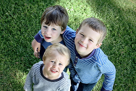 three children standing on grassy field thumbnail