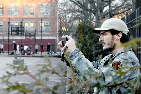 man taking photo of basketball court beside tree thumbnail