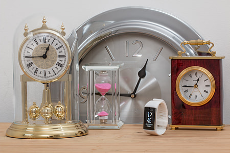 gold anniversary clock with hour glass and roman analog table clock on brown wooden table thumbnail