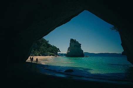 people beside shoreline facing cave thumbnail