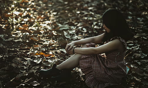 Photo of a Woman Sitting on the Ground Covered with Dried Leaves thumbnail
