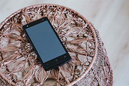Black smartphone on a miniature brown table thumbnail