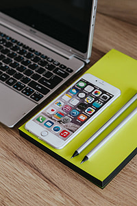 Silver Acer laptop, a white Apple iPhone and a notepad on a wooden desk thumbnail
