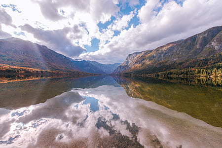 panoramic photo of lake between two mountains under thick white clouds thumbnail