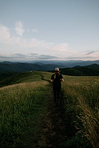 woman walking between green grass field thumbnail